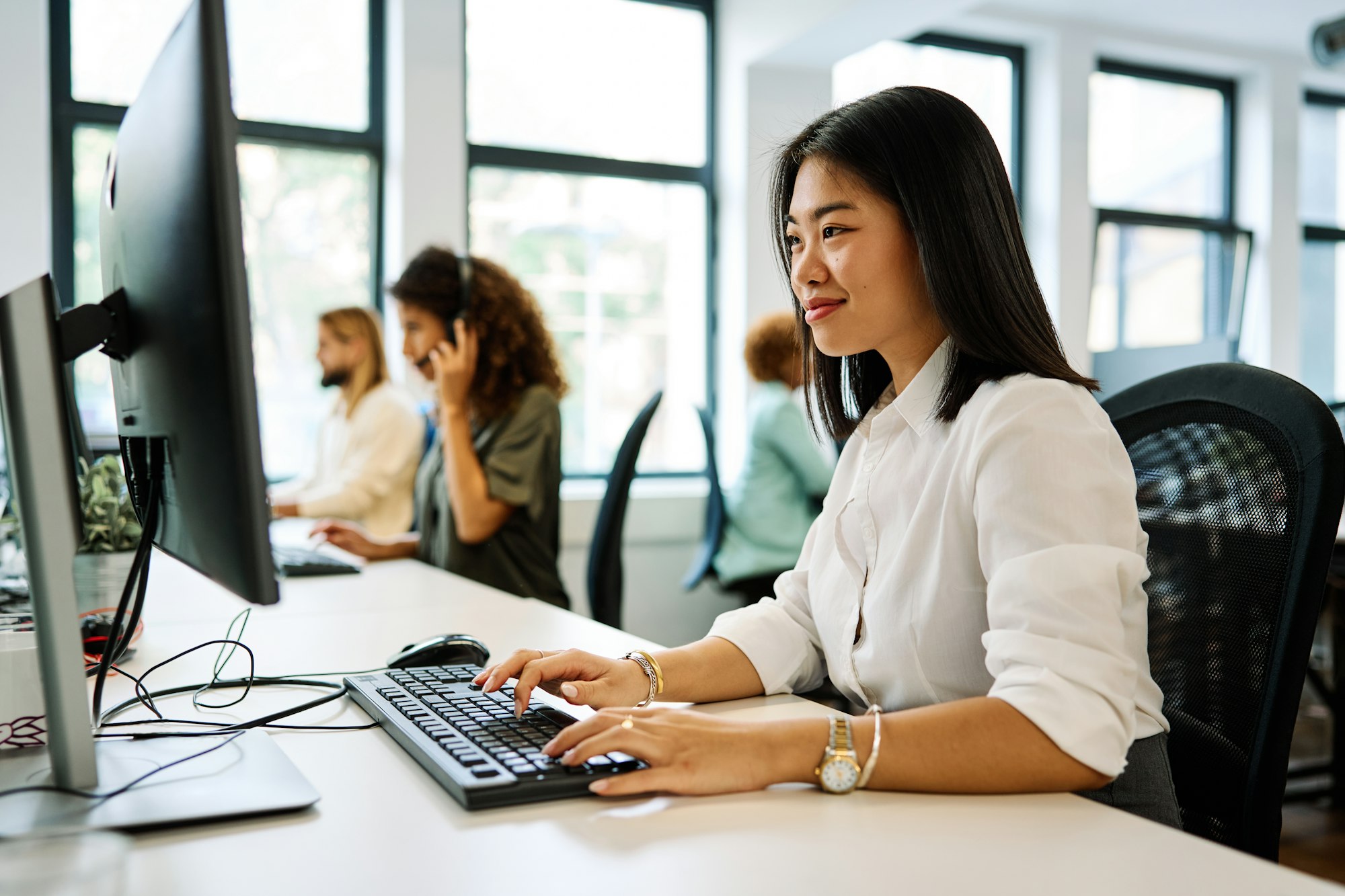 Chinese woman using computer sitting on a coworking office